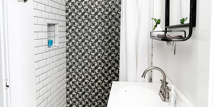 Black and White Tiled Shower Next to Vanity in Small Bathroom