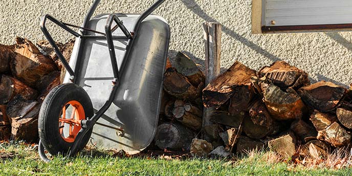 Firewood Stacked Next to House With Wheelbarrow