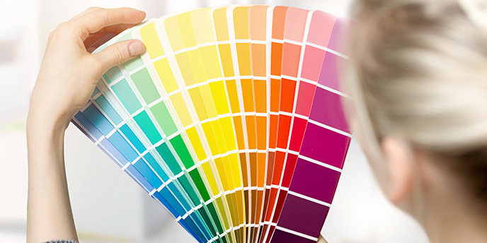 Woman Holding Up a Rainbow of Paint Color Swatches